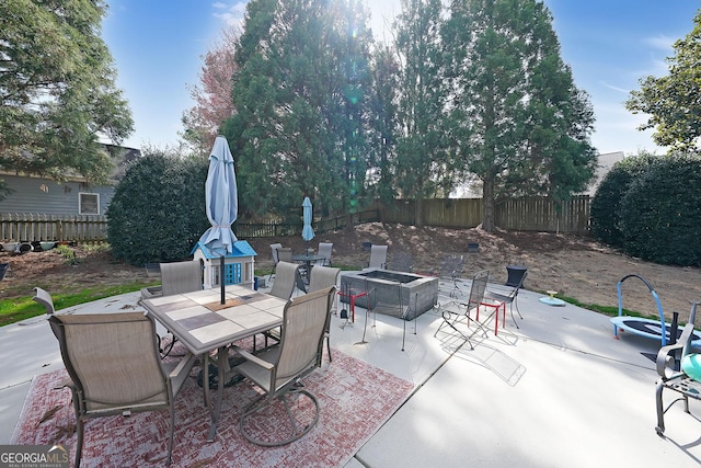 view of patio with an outdoor fire pit, outdoor dining area, and a fenced backyard