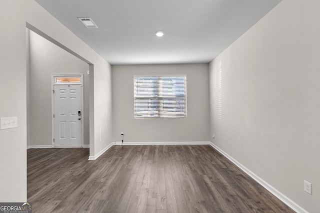 spare room featuring baseboards, visible vents, and dark wood finished floors