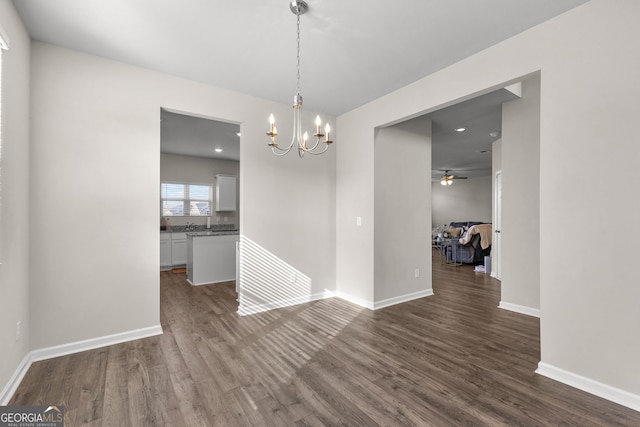 unfurnished dining area with recessed lighting, dark wood finished floors, baseboards, and ceiling fan with notable chandelier