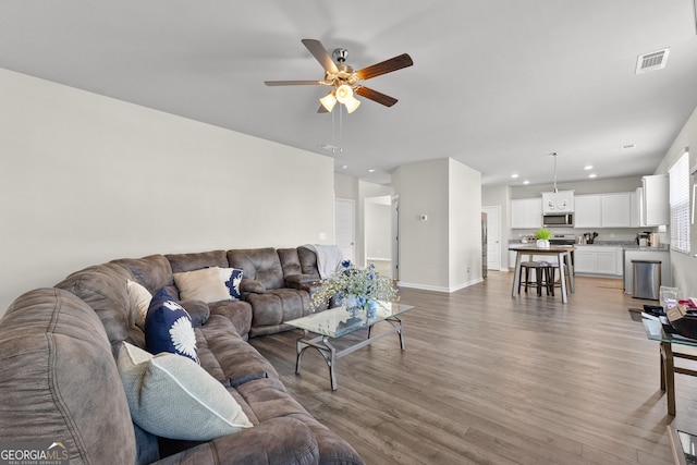 living room featuring ceiling fan, recessed lighting, visible vents, baseboards, and light wood finished floors