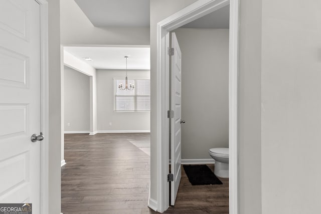 bathroom featuring a chandelier, baseboards, toilet, and wood finished floors