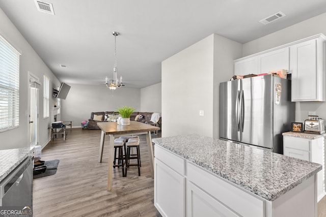 kitchen with stainless steel appliances, light wood-style flooring, visible vents, and white cabinets