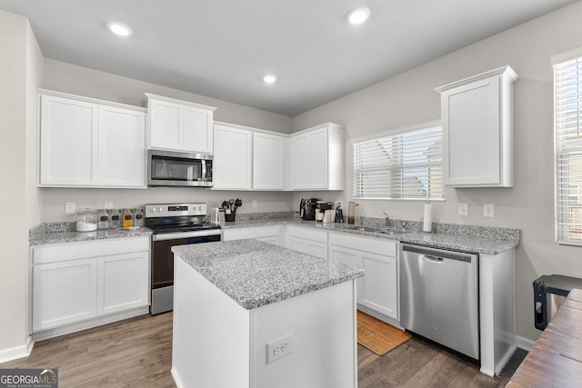 kitchen featuring appliances with stainless steel finishes, white cabinets, a sink, and wood finished floors