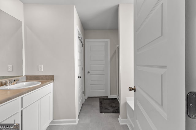 bathroom with a shower with door, vanity, and baseboards