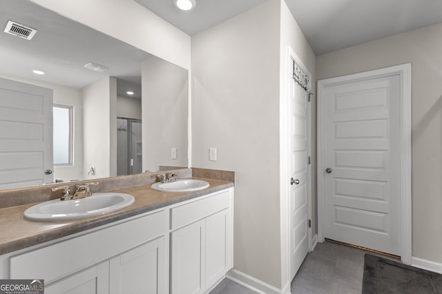 bathroom with double vanity, baseboards, visible vents, and a sink