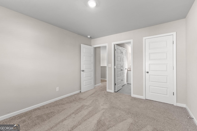 unfurnished bedroom featuring carpet floors, ensuite bath, and baseboards