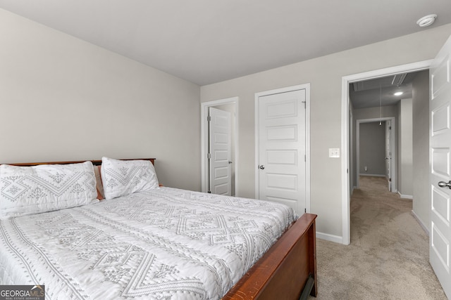 bedroom with light carpet, attic access, and baseboards