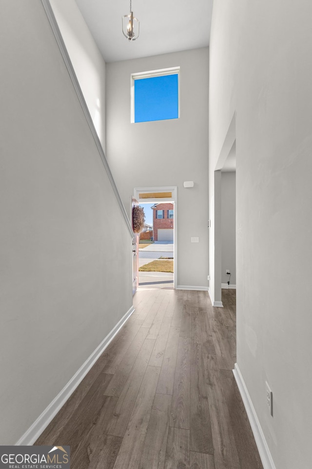 entrance foyer featuring a notable chandelier, a high ceiling, baseboards, and wood finished floors