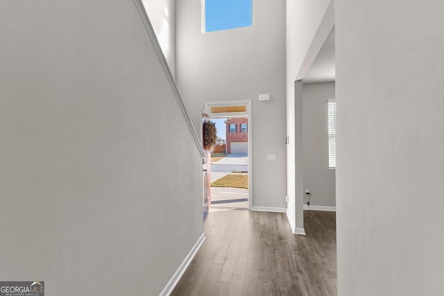 foyer entrance with dark wood finished floors, a towering ceiling, and baseboards