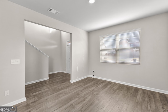 unfurnished room with baseboards, visible vents, and wood finished floors