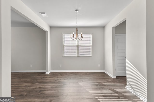 unfurnished dining area with baseboards, visible vents, a chandelier, and dark wood-type flooring