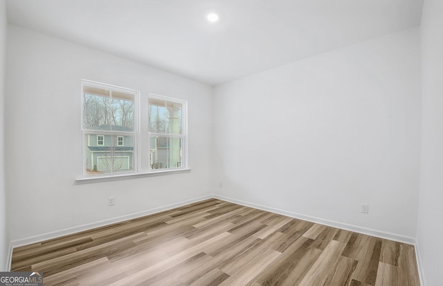 spare room featuring baseboards and wood finished floors