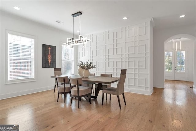 dining room with light wood-style floors, visible vents, arched walkways, and recessed lighting