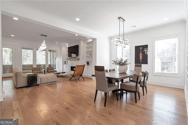 dining space featuring light wood finished floors, a fireplace, and recessed lighting