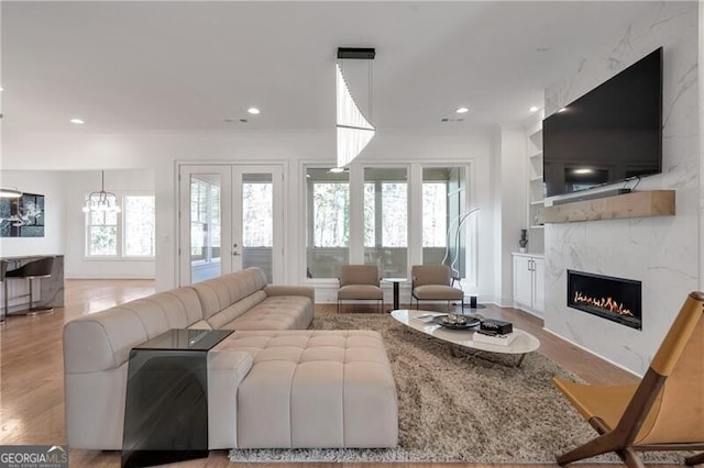 living area featuring built in features, french doors, a fireplace, recessed lighting, and wood finished floors