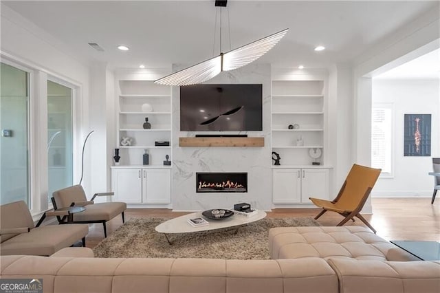 living area featuring light wood-type flooring, built in shelves, a fireplace, and recessed lighting