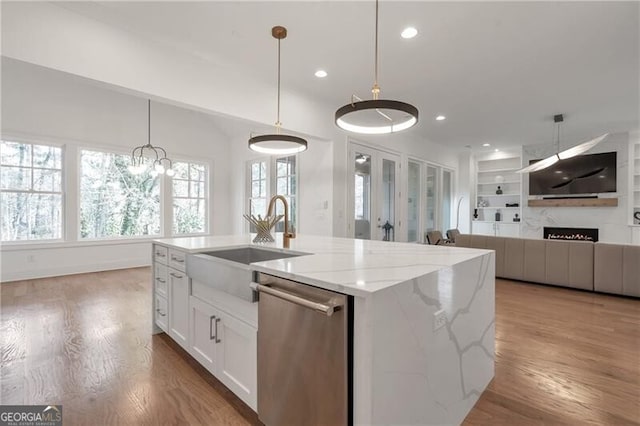 kitchen with wood finished floors, a sink, white cabinetry, built in features, and dishwasher