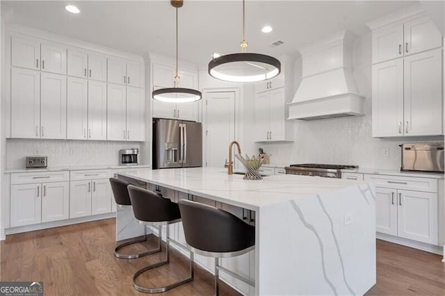 kitchen with custom range hood, white cabinets, a sink, wood finished floors, and stainless steel fridge with ice dispenser