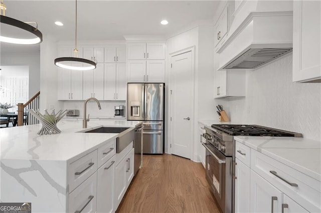 kitchen featuring custom range hood, white cabinetry, stainless steel appliances, and wood finished floors