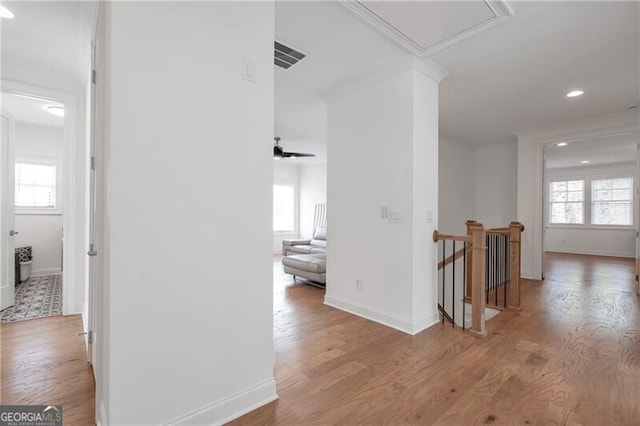 hallway with a healthy amount of sunlight, visible vents, wood finished floors, and an upstairs landing