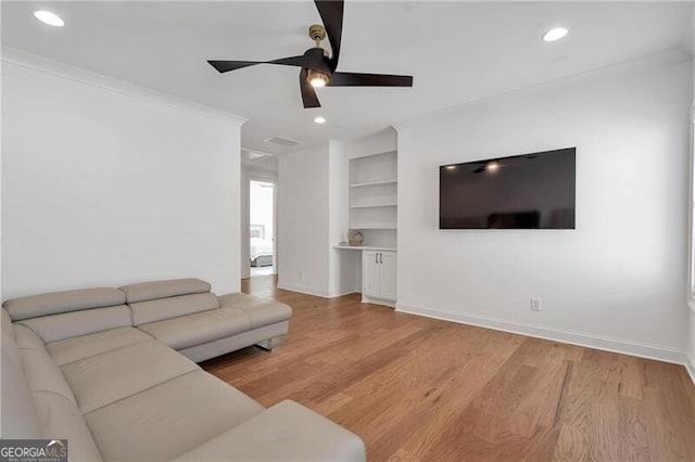 living area with built in features, recessed lighting, light wood-style flooring, ornamental molding, and baseboards