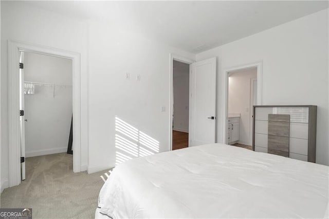 bedroom featuring light carpet, a spacious closet, a closet, and baseboards