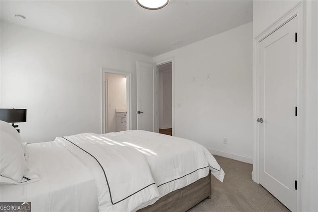 bedroom with light carpet, baseboards, and ensuite bathroom