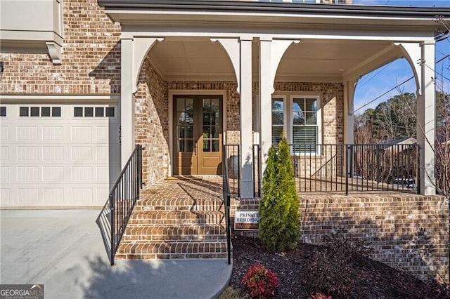 property entrance featuring a garage, french doors, brick siding, and concrete driveway