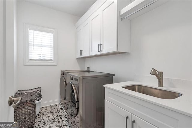 washroom with cabinet space, baseboards, tile patterned floors, washing machine and clothes dryer, and a sink