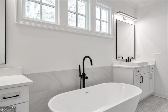 full bath with a freestanding bath, plenty of natural light, and vanity