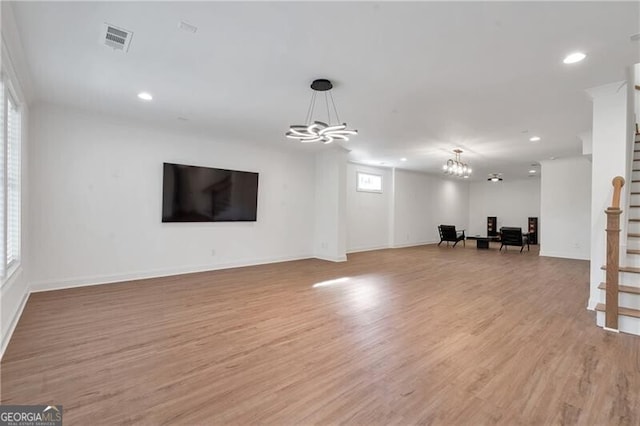 unfurnished living room with visible vents, light wood-style flooring, stairway, a notable chandelier, and recessed lighting