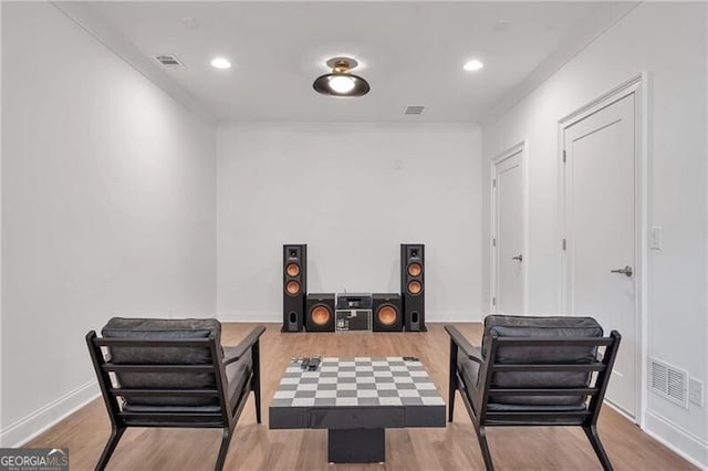 living area featuring visible vents, baseboards, wood finished floors, crown molding, and recessed lighting