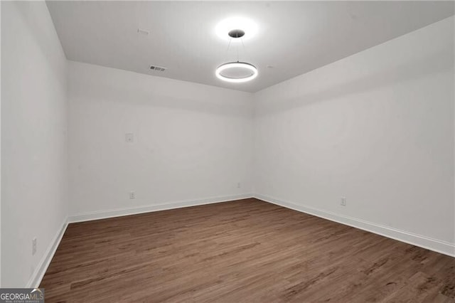 spare room featuring baseboards, visible vents, and wood finished floors