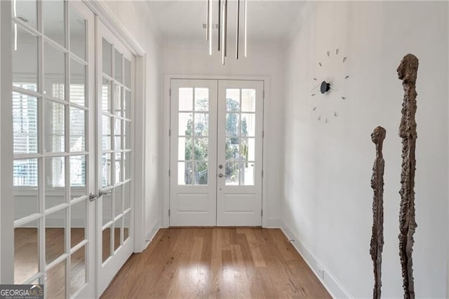 doorway to outside with french doors, light wood-style flooring, and baseboards