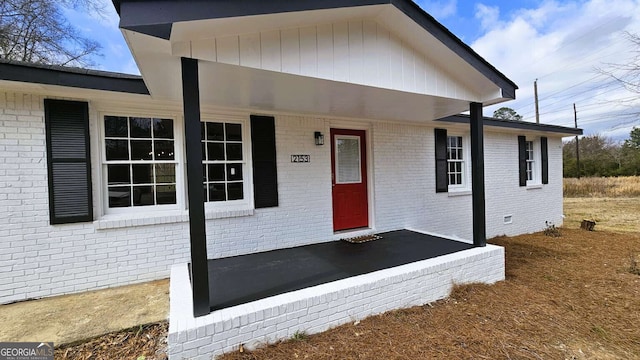 entrance to property featuring crawl space and brick siding