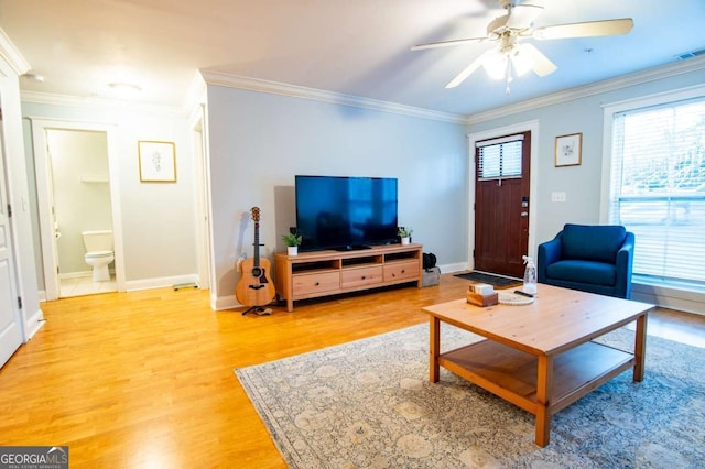 living room featuring ornamental molding, light wood-type flooring, baseboards, and a ceiling fan