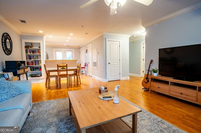 living area with light wood-type flooring, baseboards, visible vents, and crown molding