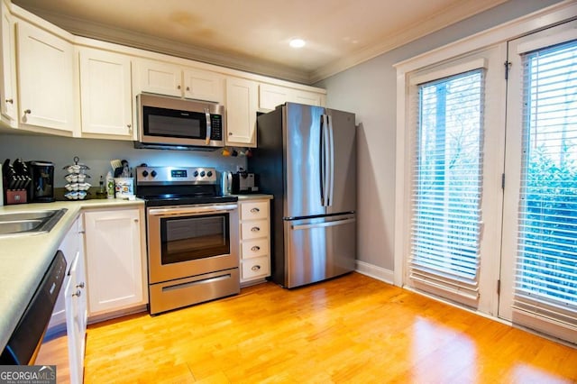 kitchen featuring light wood finished floors, white cabinetry, stainless steel appliances, and crown molding