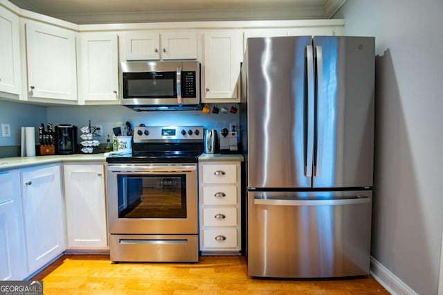 kitchen with light wood finished floors, light countertops, appliances with stainless steel finishes, white cabinetry, and baseboards