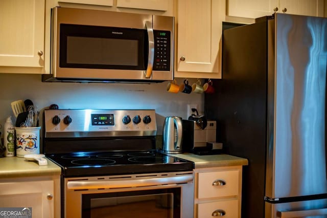 kitchen with stainless steel appliances, light countertops, and white cabinetry