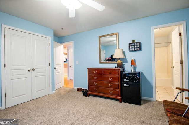 carpeted bedroom featuring a closet, baseboards, ceiling fan, and ensuite bath