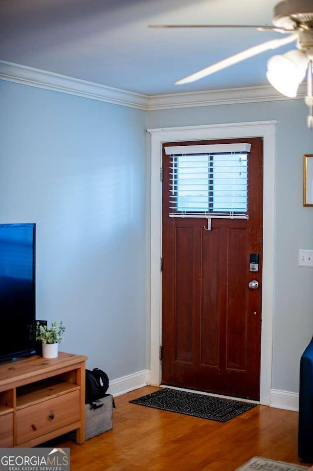 foyer entrance with crown molding, baseboards, and wood finished floors