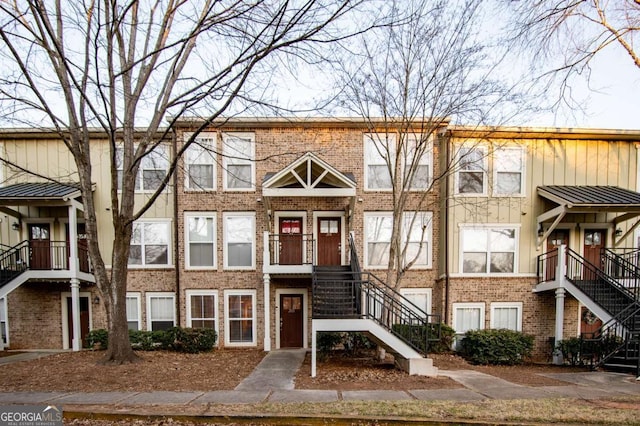 view of front of home featuring stairs, board and batten siding, and brick siding