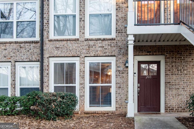 property entrance featuring brick siding and a balcony