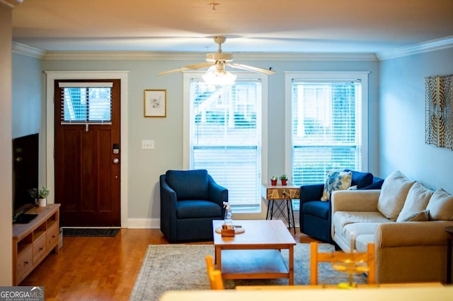 living area featuring a ceiling fan, baseboards, ornamental molding, and wood finished floors