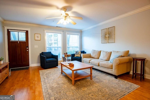 living area with baseboards, ceiling fan, wood finished floors, and crown molding