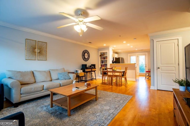 living room featuring baseboards, a ceiling fan, light wood-style flooring, crown molding, and recessed lighting