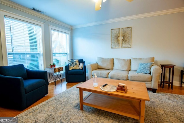 living area featuring visible vents, crown molding, baseboards, and wood finished floors