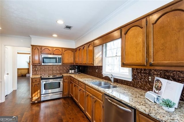 kitchen featuring appliances with stainless steel finishes, brown cabinetry, a sink, and visible vents