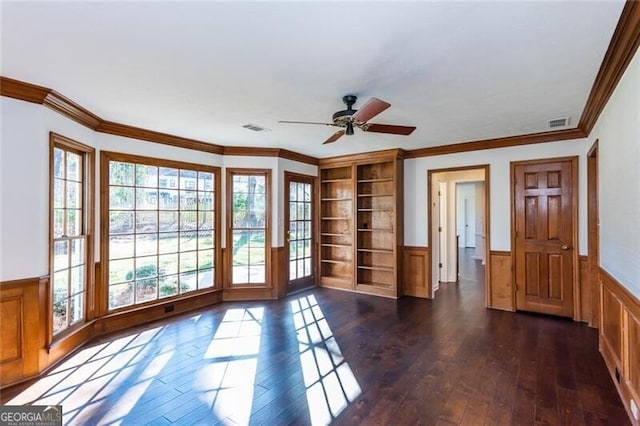 interior space featuring crown molding, a wainscoted wall, dark wood finished floors, and visible vents